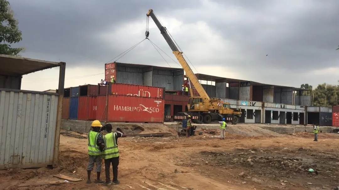 Workers beside a row of converted shipping containers